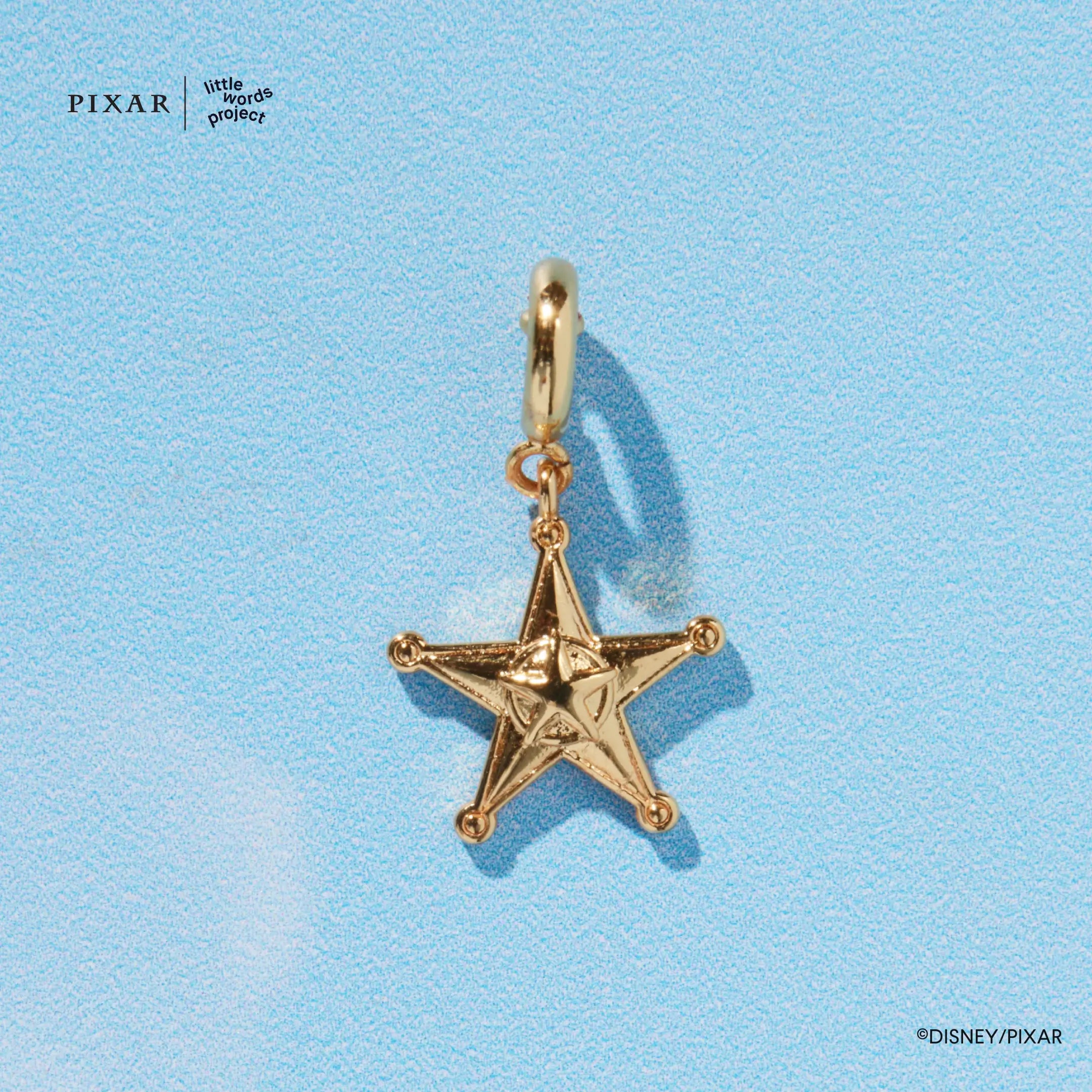 Gold sheriff badge star charm from the Reach for the Sky Toy Story set, detail on blue