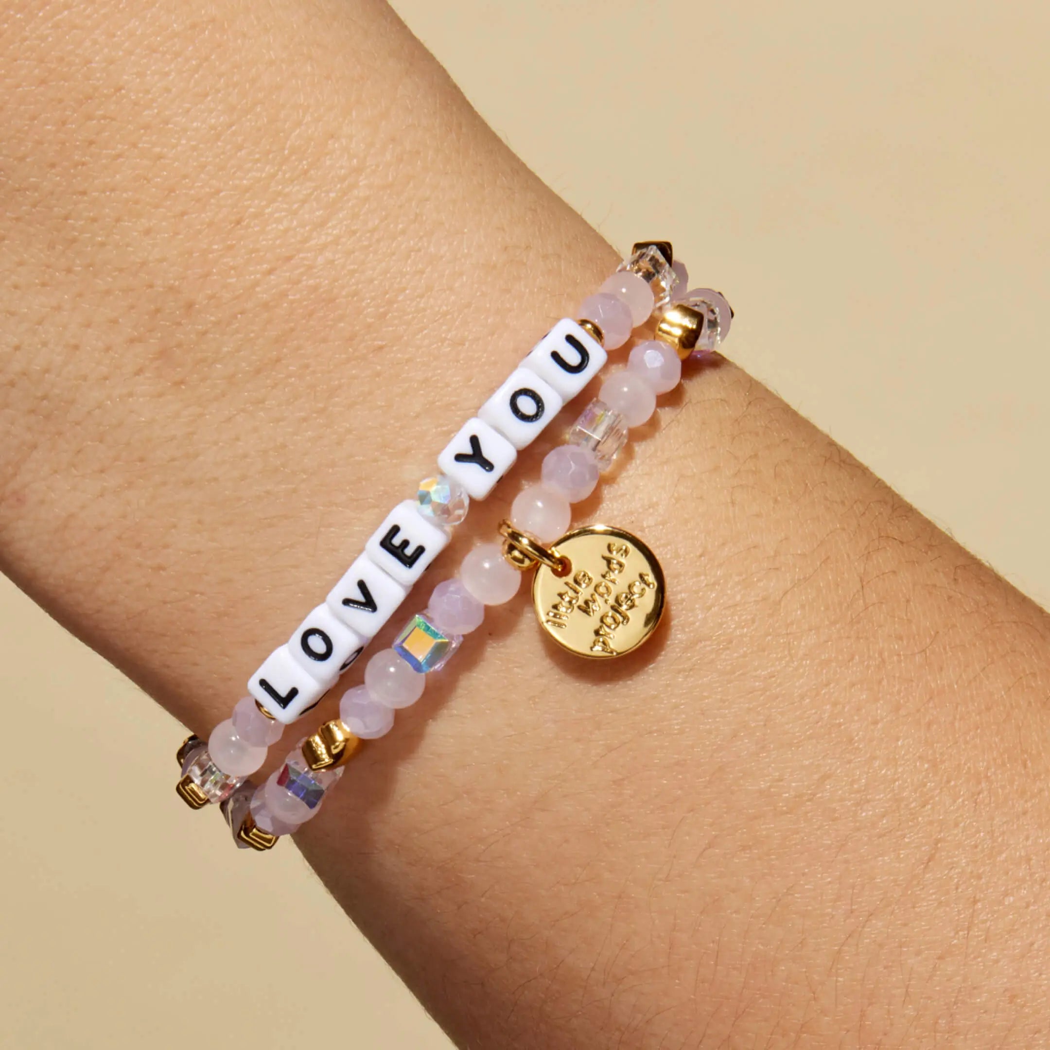 Bracelet with 'LOVE YOU' beads on a wrist against a beige background