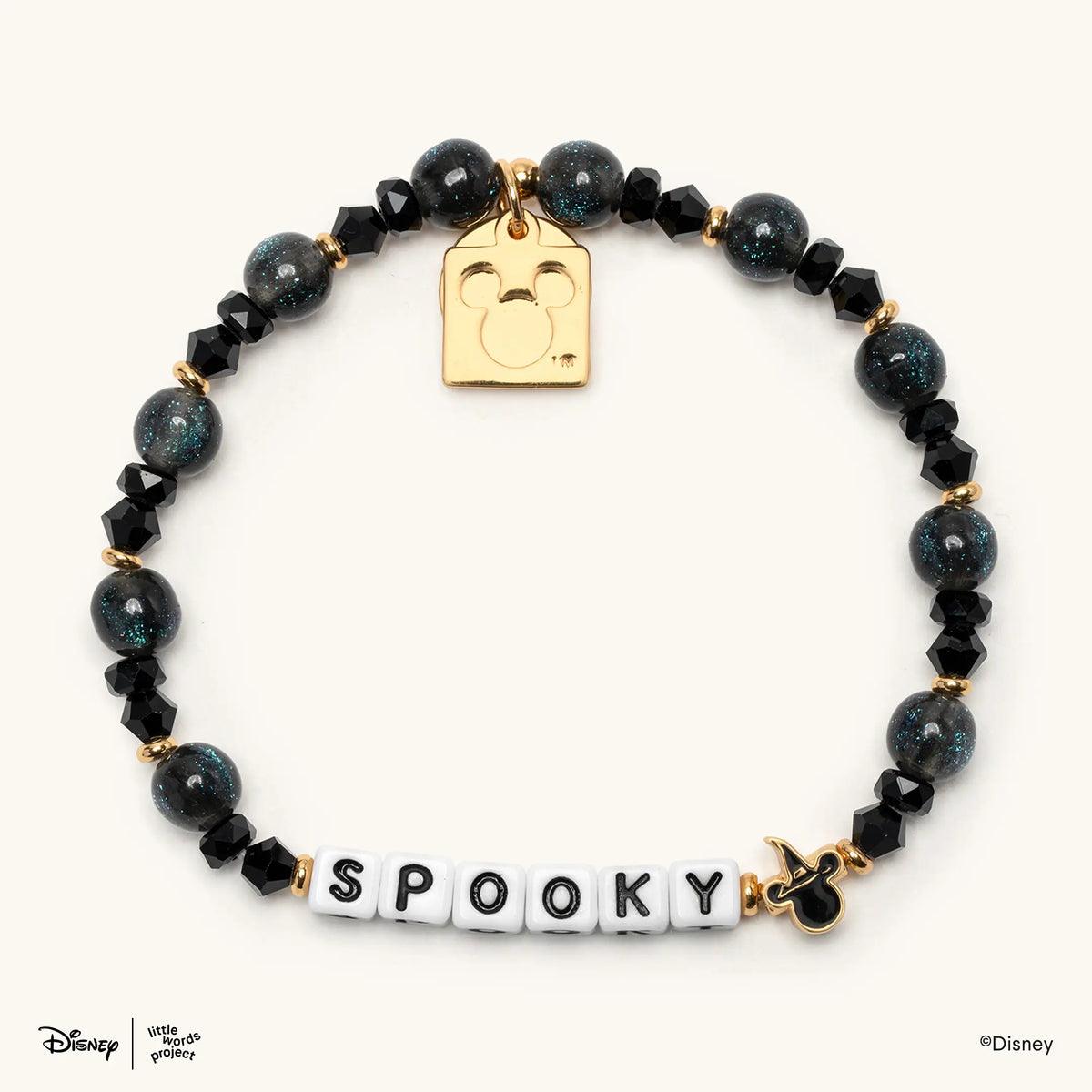 Spooky Disney's Mickey & Friends beaded bracelet in black and dark shimmer beads with white letter beads and a gold Mickey Mouse witch hat casted bead, flat-lay