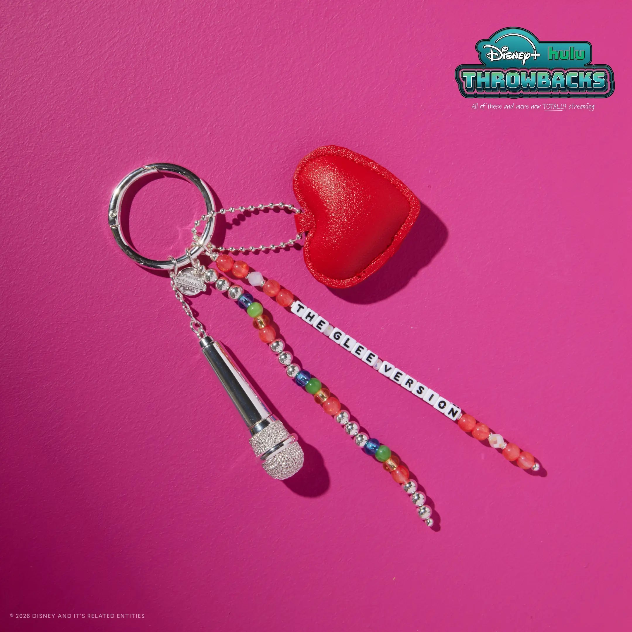 The Glee Version Disney+ Hulu Throwbacks bag charm on a hot pink background showing the red heart and silver microphone charms
