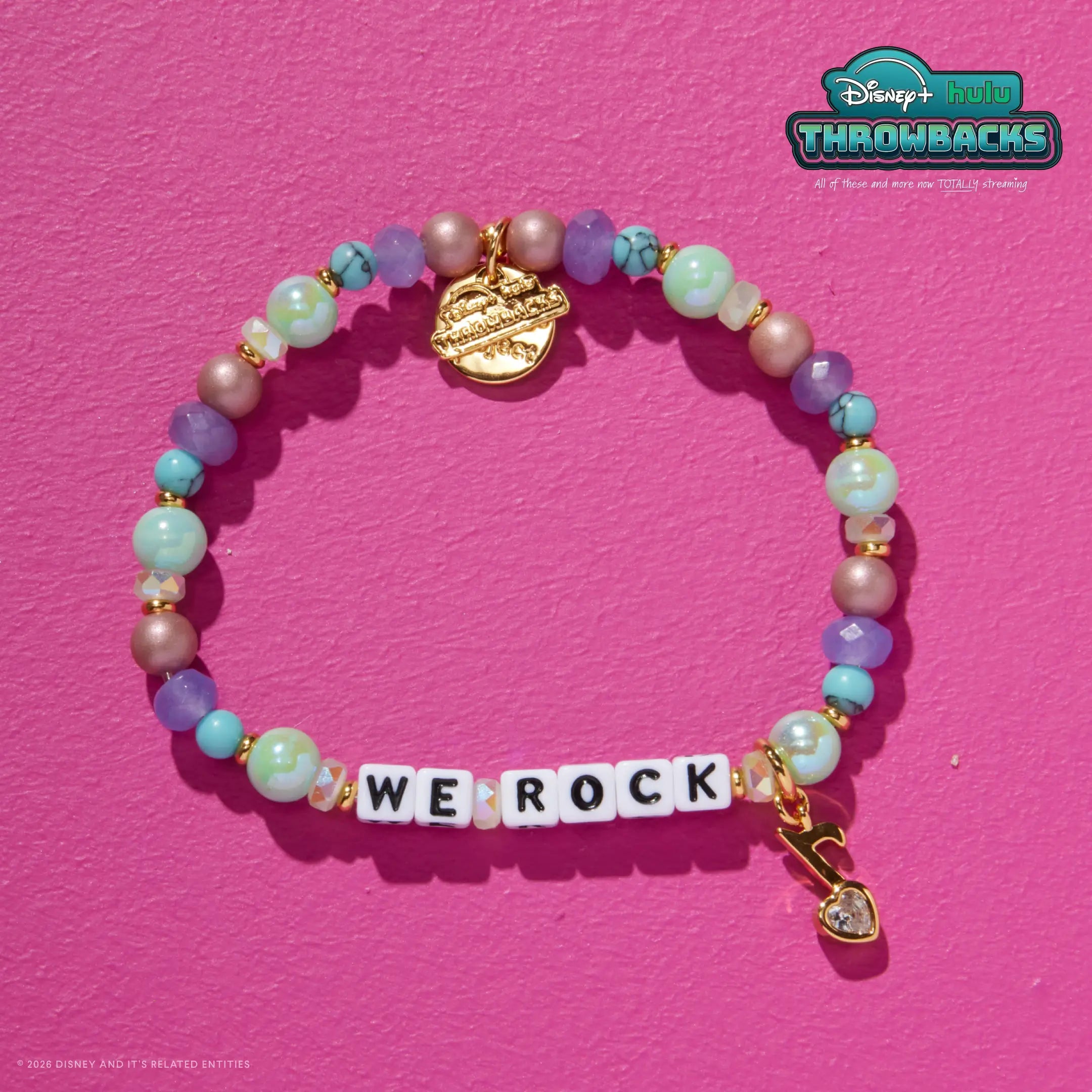 We Rock Disney+ Hulu Throwbacks bracelet on a hot pink background showing the gold crystal heart charm and Throwbacks logo tag